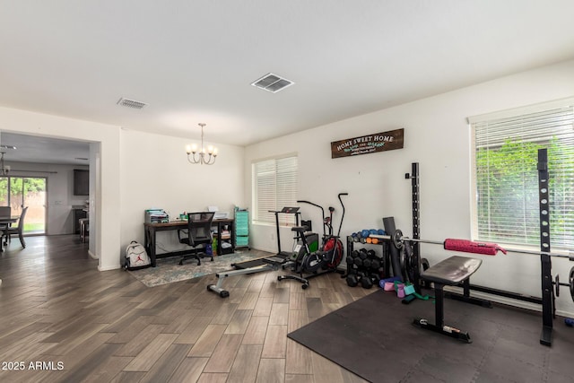 workout room with visible vents, a notable chandelier, and wood finished floors