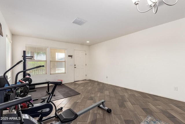 workout room with visible vents, an inviting chandelier, and dark wood-style floors