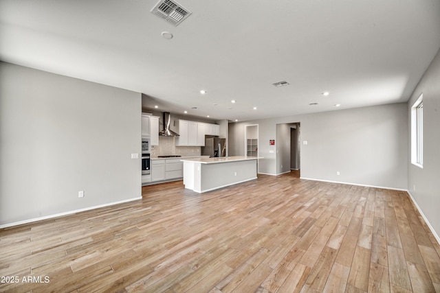 unfurnished living room with recessed lighting, visible vents, baseboards, and light wood finished floors