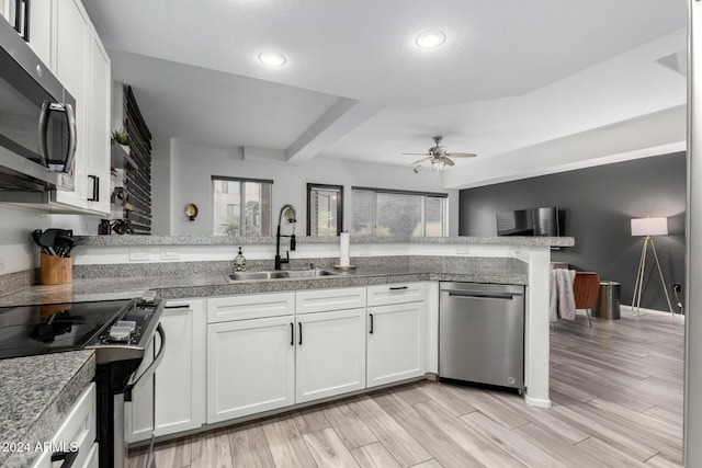 kitchen featuring kitchen peninsula, stainless steel appliances, white cabinetry, and sink