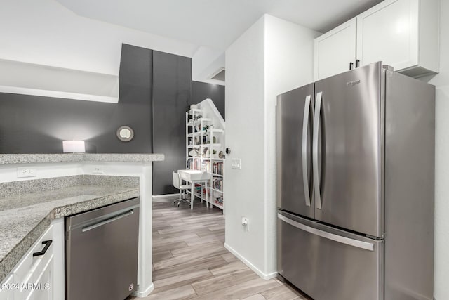 kitchen featuring white cabinets, stainless steel appliances, and light stone countertops