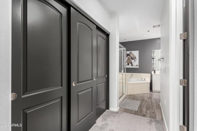 bathroom with hardwood / wood-style flooring and independent shower and bath