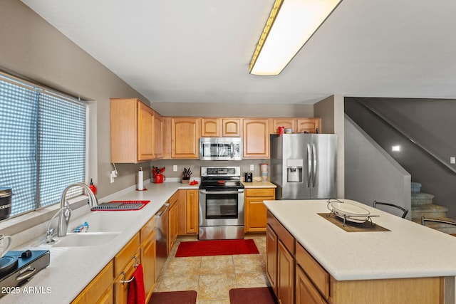 kitchen with appliances with stainless steel finishes, a sink, light countertops, and a center island