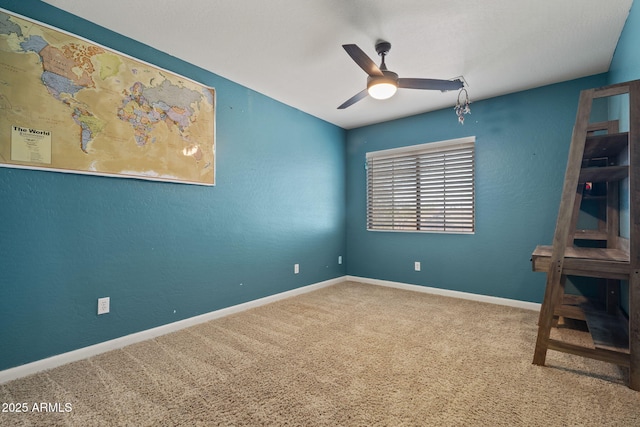 carpeted spare room featuring ceiling fan and baseboards