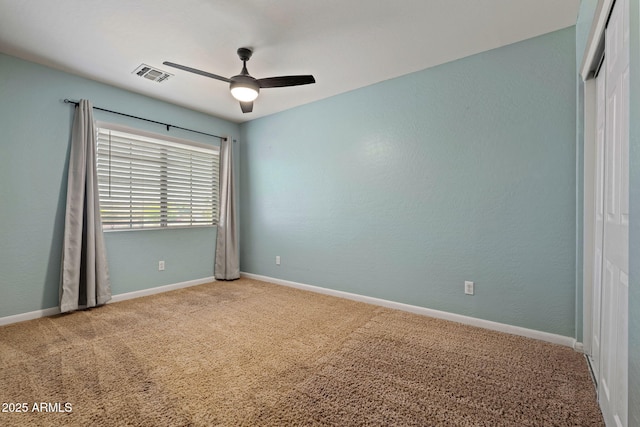 carpeted empty room featuring ceiling fan and baseboards