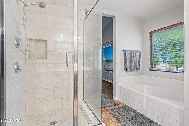 bathroom with a stall shower, a garden tub, and baseboards