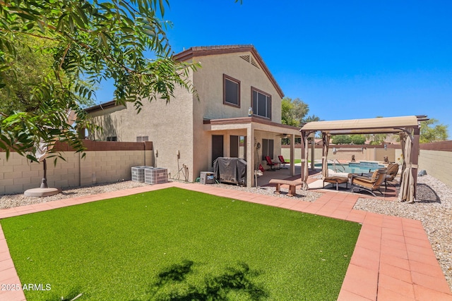 rear view of house with stucco siding, a patio area, and a gazebo
