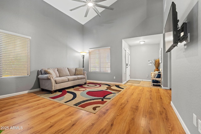 living room with ceiling fan, wood finished floors, high vaulted ceiling, and baseboards