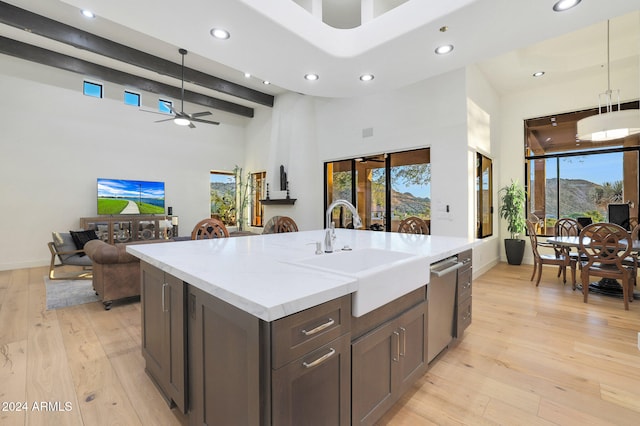 kitchen featuring light hardwood / wood-style floors, decorative light fixtures, a kitchen island with sink, and sink