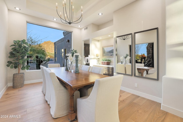 dining room featuring a tray ceiling, light hardwood / wood-style flooring, and a notable chandelier