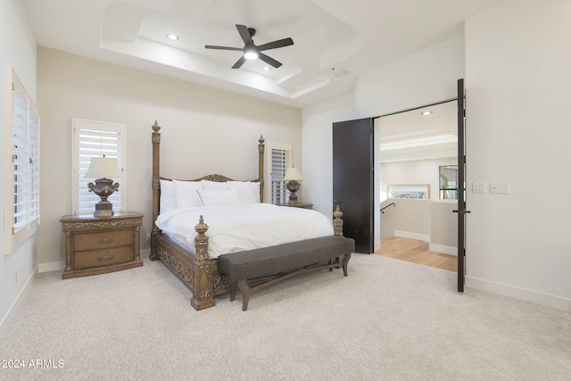 carpeted bedroom featuring a raised ceiling and ceiling fan