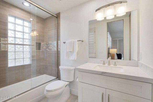 full bathroom featuring enclosed tub / shower combo, vanity, and toilet