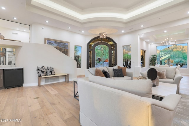 living room featuring a high ceiling, a raised ceiling, and light hardwood / wood-style floors