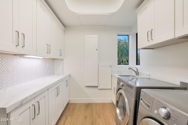 laundry area with cabinets, sink, light hardwood / wood-style floors, and washing machine and dryer