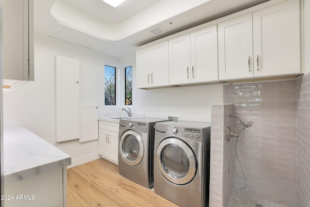 laundry area featuring cabinets, washing machine and clothes dryer, sink, and light wood-type flooring