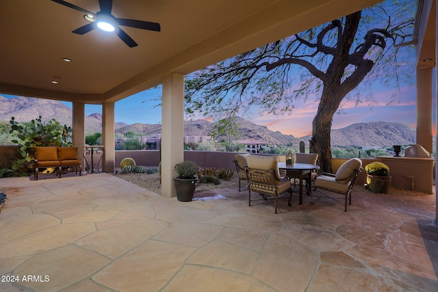 patio terrace at dusk featuring a mountain view and ceiling fan