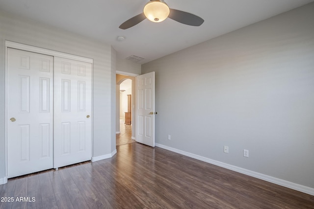 3649 E Hazeltine Way, Chandler, AZ 85249 - unfurnished bedroom with arched walkways, baseboards, dark wood finished floors, a closet, and a ceiling fan