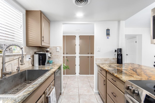 kitchen featuring sink, appliances with stainless steel finishes, backsplash, light stone countertops, and light tile patterned flooring