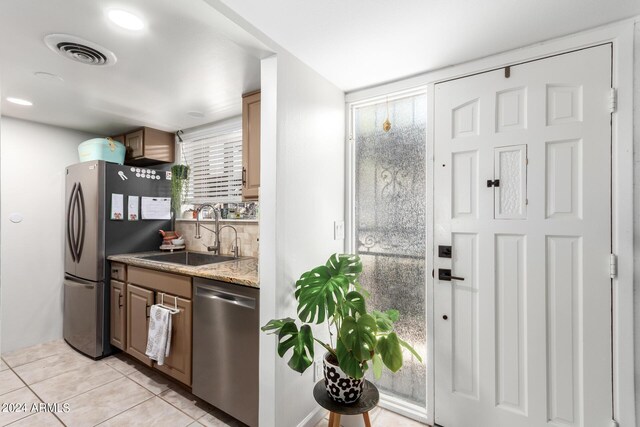 kitchen featuring light stone counters, stainless steel appliances, light tile patterned flooring, and sink