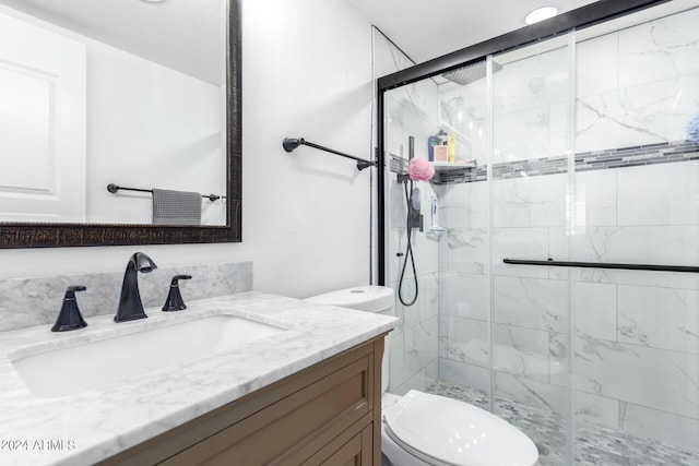 bathroom with a shower with door, vanity, and toilet