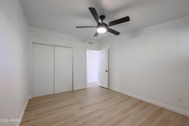 unfurnished bedroom with light wood-type flooring, visible vents, baseboards, and a closet