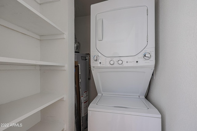 clothes washing area featuring stacked washer / drying machine, water heater, and laundry area