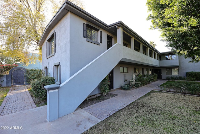 exterior space featuring stucco siding and a gate