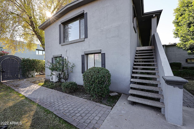 view of home's exterior featuring stucco siding, stairs, and a gate