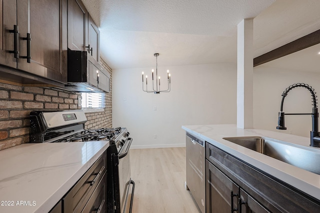 kitchen with a sink, dark brown cabinetry, appliances with stainless steel finishes, pendant lighting, and light wood-type flooring