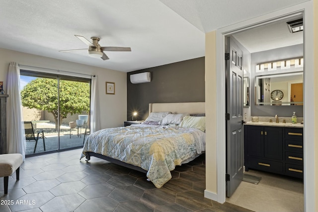 bedroom with connected bathroom, sink, access to outside, ceiling fan, and a wall unit AC