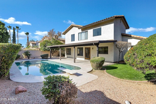 back of property featuring a fenced in pool and a patio