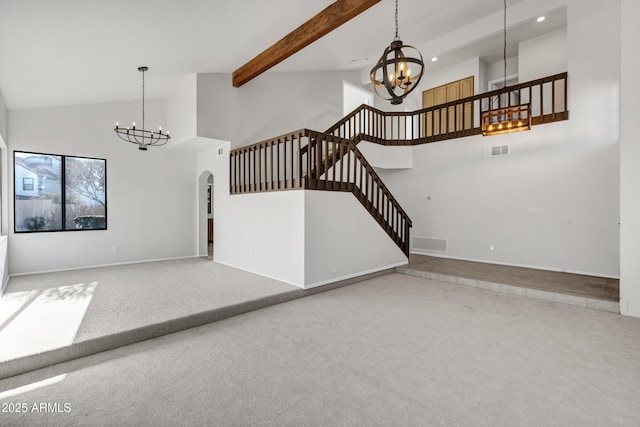 unfurnished living room featuring carpet, an inviting chandelier, and high vaulted ceiling