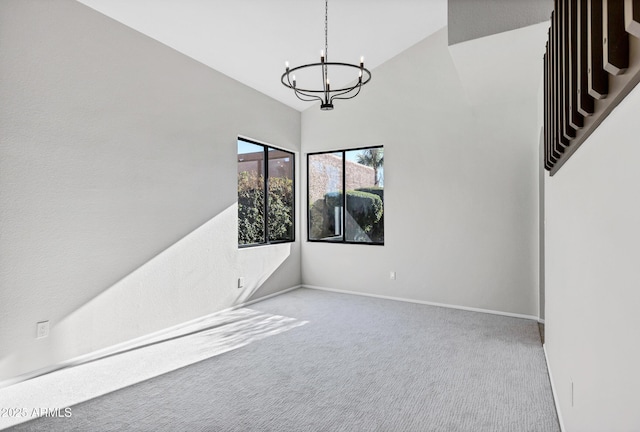 carpeted spare room featuring a chandelier and vaulted ceiling