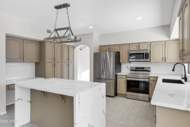 kitchen featuring pendant lighting, appliances with stainless steel finishes, sink, a kitchen island, and decorative backsplash