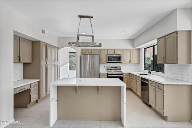 kitchen with a kitchen island, backsplash, sink, and stainless steel appliances