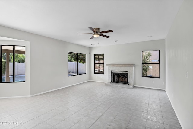 unfurnished living room with ceiling fan, light tile patterned floors, a wealth of natural light, and a high end fireplace