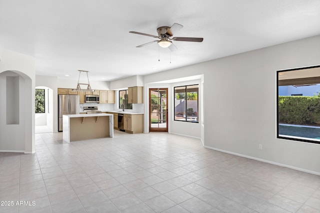 unfurnished living room with sink, light tile patterned flooring, and ceiling fan