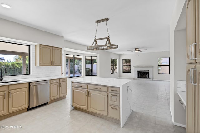 kitchen with stainless steel dishwasher, ceiling fan, sink, tasteful backsplash, and a center island