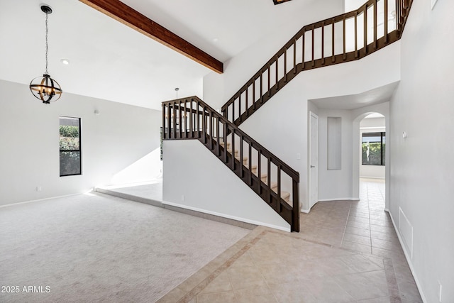 stairs featuring a chandelier, a wealth of natural light, and beam ceiling