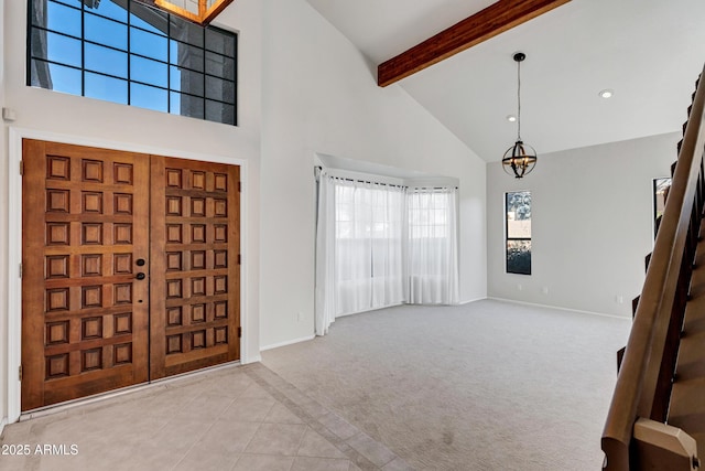 carpeted foyer entrance with an inviting chandelier, beam ceiling, and a high ceiling