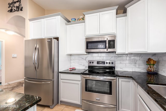 kitchen featuring white cabinets, decorative backsplash, light tile patterned floors, and stainless steel appliances