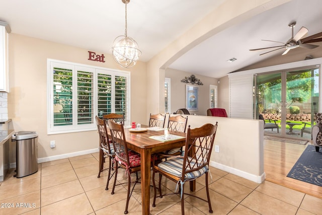 tiled dining room featuring lofted ceiling, a healthy amount of sunlight, and ceiling fan with notable chandelier