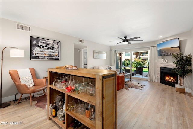 interior space with ceiling fan, a fireplace, and light wood-type flooring