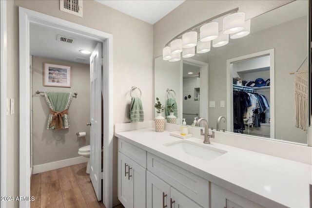 bathroom with wood-type flooring, vanity, and toilet