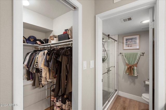 bathroom featuring hardwood / wood-style flooring, toilet, and a shower with shower door