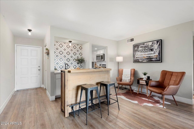 kitchen featuring a breakfast bar, light wood-type flooring, and appliances with stainless steel finishes