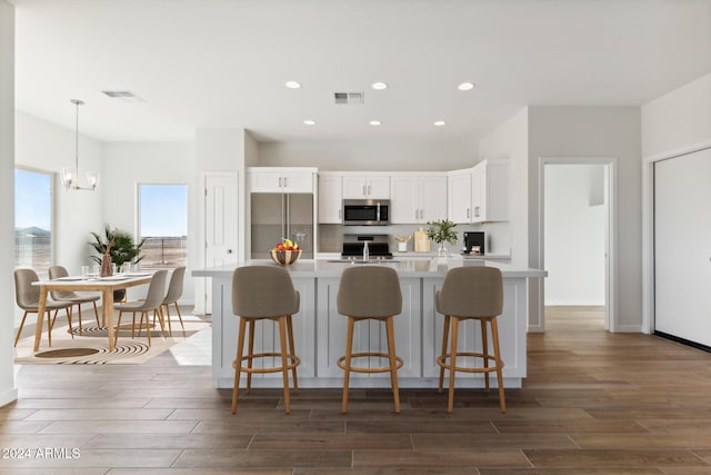 kitchen with appliances with stainless steel finishes, decorative light fixtures, white cabinetry, and dark hardwood / wood-style floors