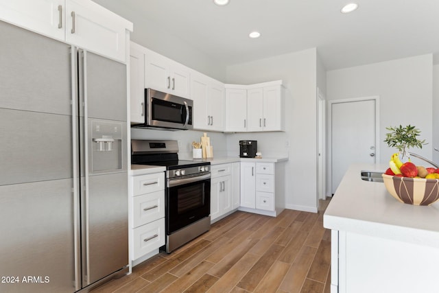 kitchen with white cabinets, appliances with stainless steel finishes, and light hardwood / wood-style flooring