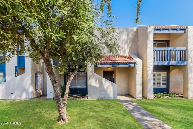 back of house with a balcony and a yard