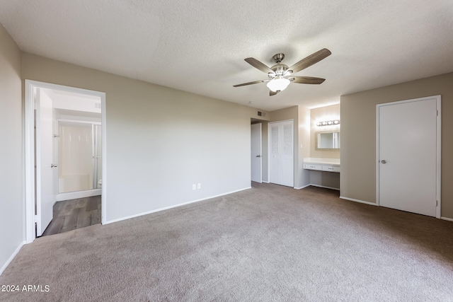 unfurnished bedroom featuring ensuite bath, a textured ceiling, ceiling fan, and carpet